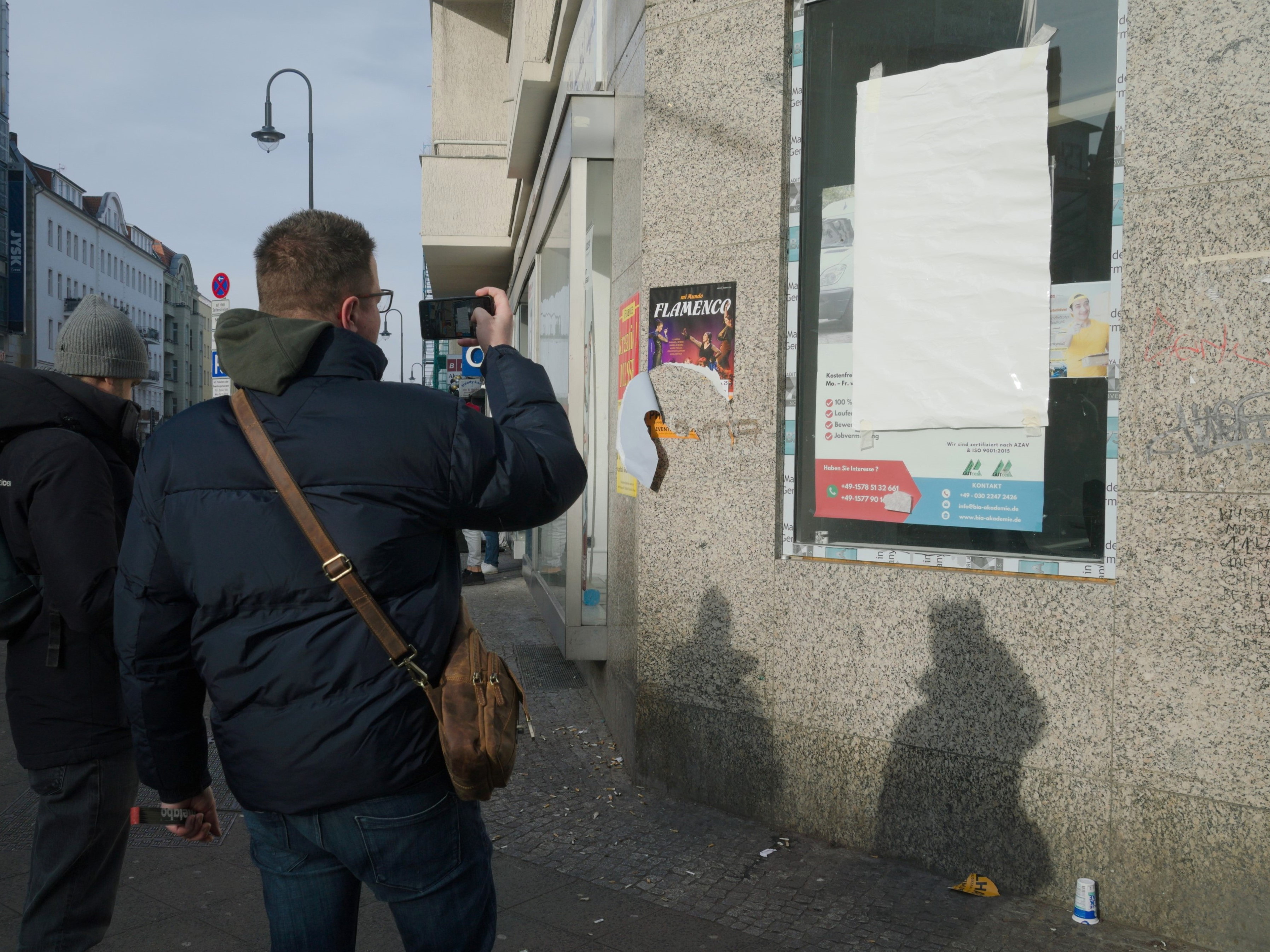 Una persona fotografía un cartel en blanco. Serie 'el soporte' de Ibán Ojea: exploración de fotografía conceptual en Berlín-Neukölln.