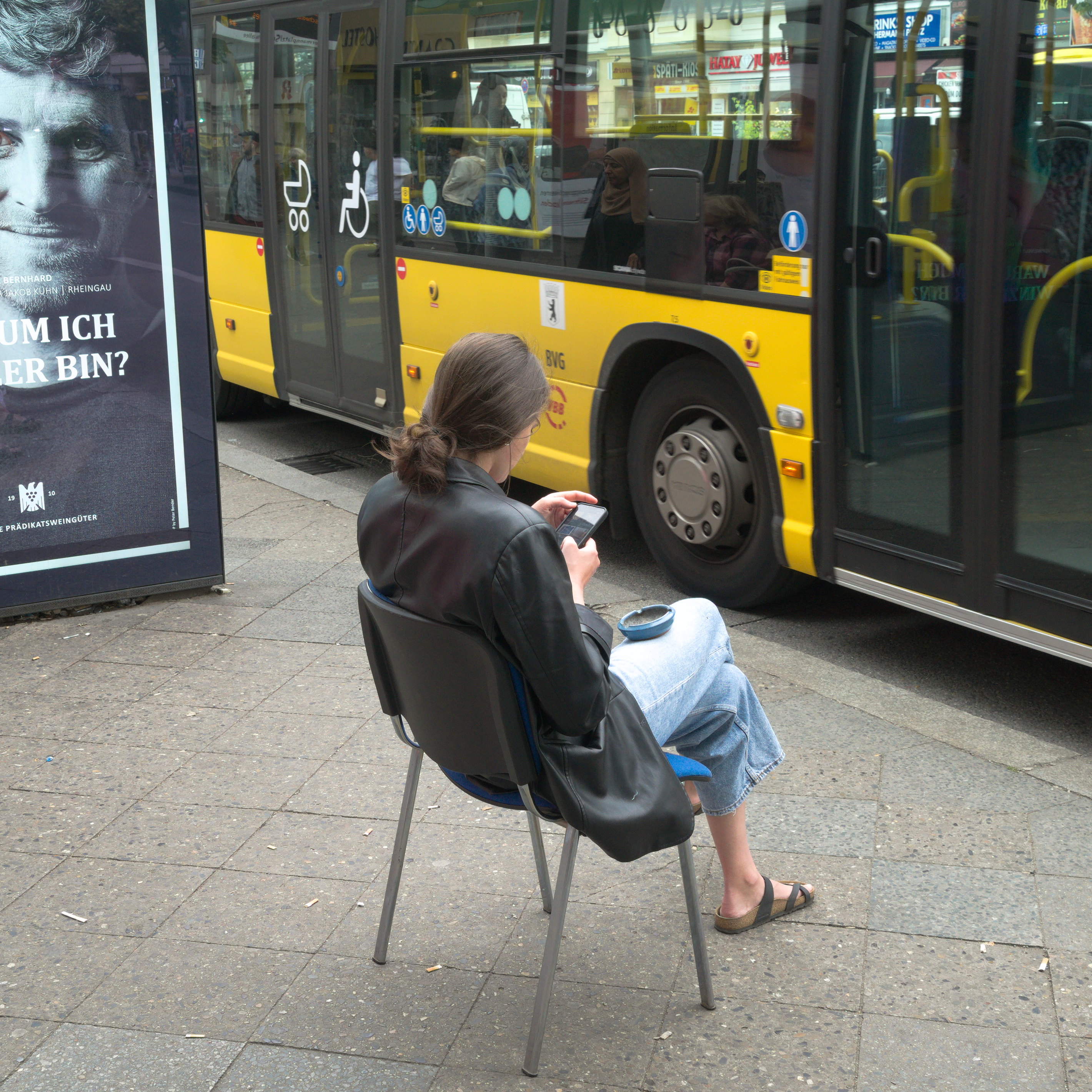 Una mujer esperando el autobús sentada en una silla común. De la serie 'el soporte' por Ibán Ojea.