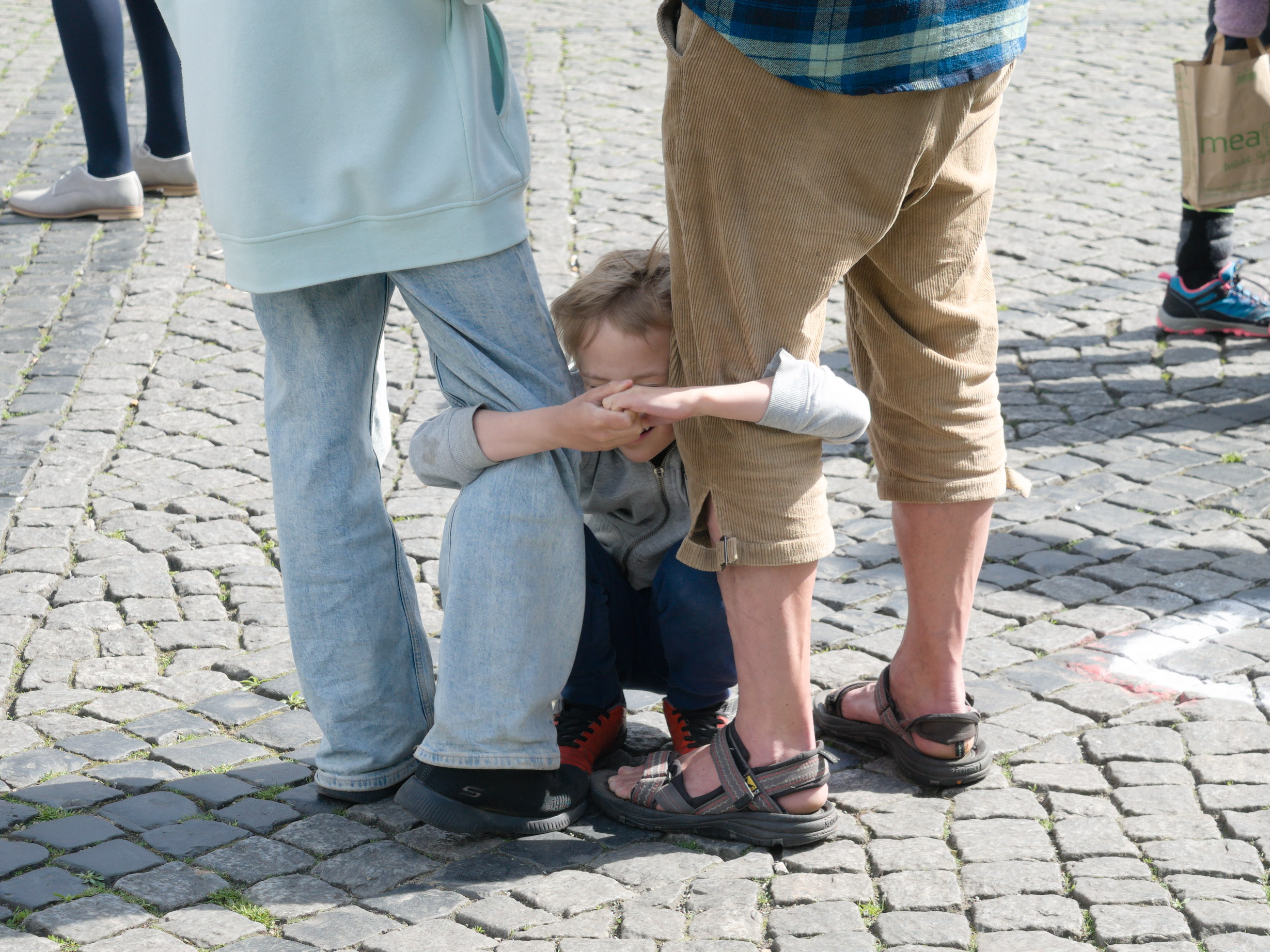 Un niño se agarra con fuerza a las piernas de sus padres. Serie 'el soporte', fotografía de Ibán Ojea. Berlín.