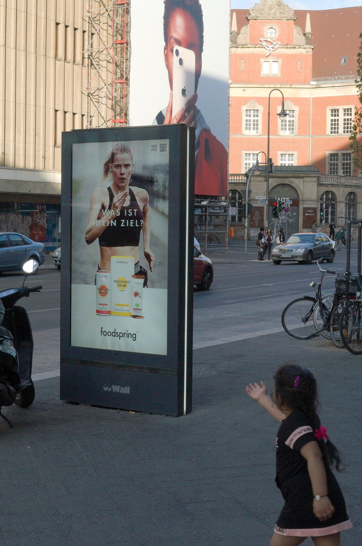 Una niña señala un cartel publicitario. Serie 'el soporte' de Ibán Ojea: exploración de fotografía conceptual. Berlín.