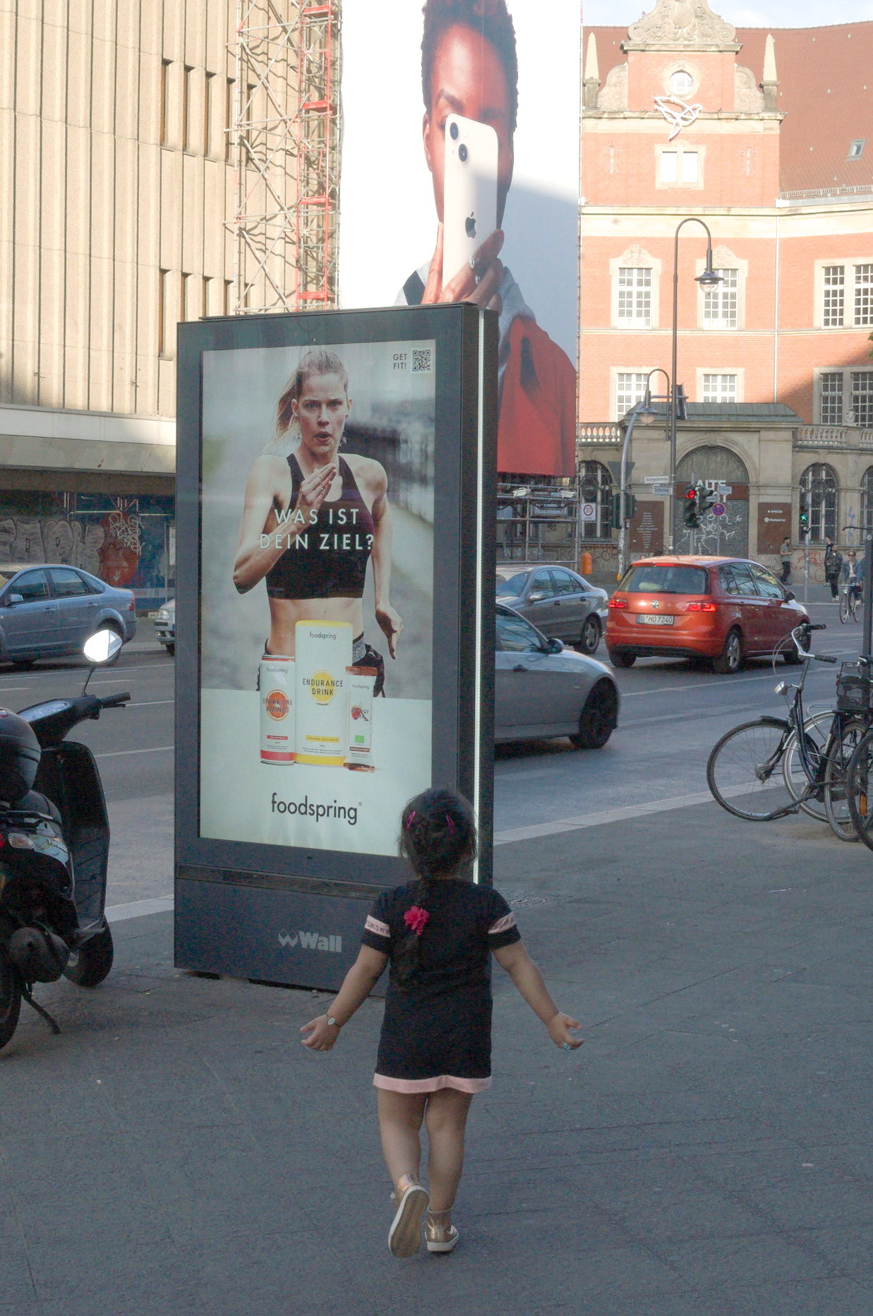 La niña se acerca al cartel publictario con los brazos abiertos. Berlín. Serie 'el soporte' de Ibán Ojea.