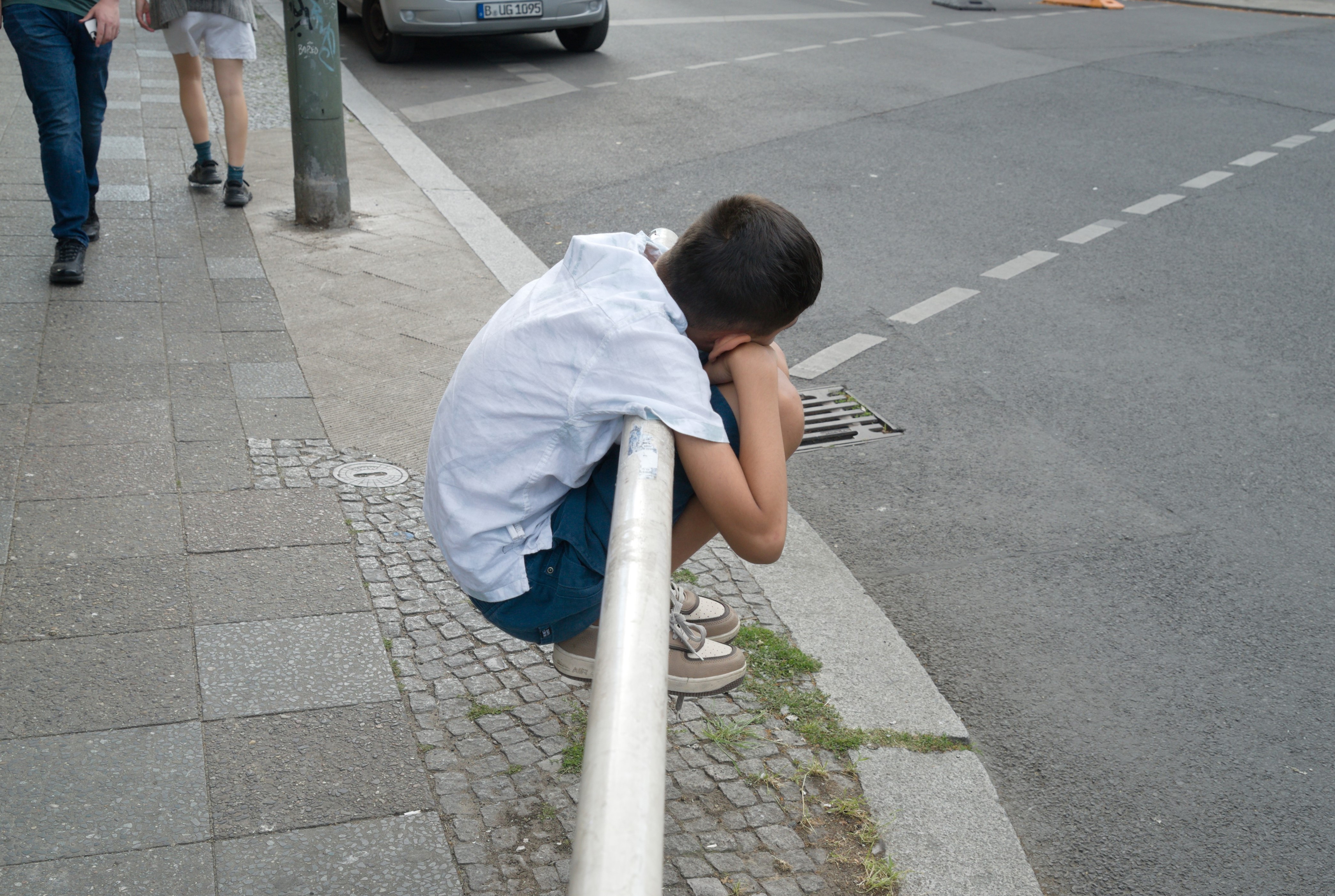 Niño ensimismado usando una valla como soporte. Serie 'el soporte', fotografía de Ibán Ojea. Berlín.