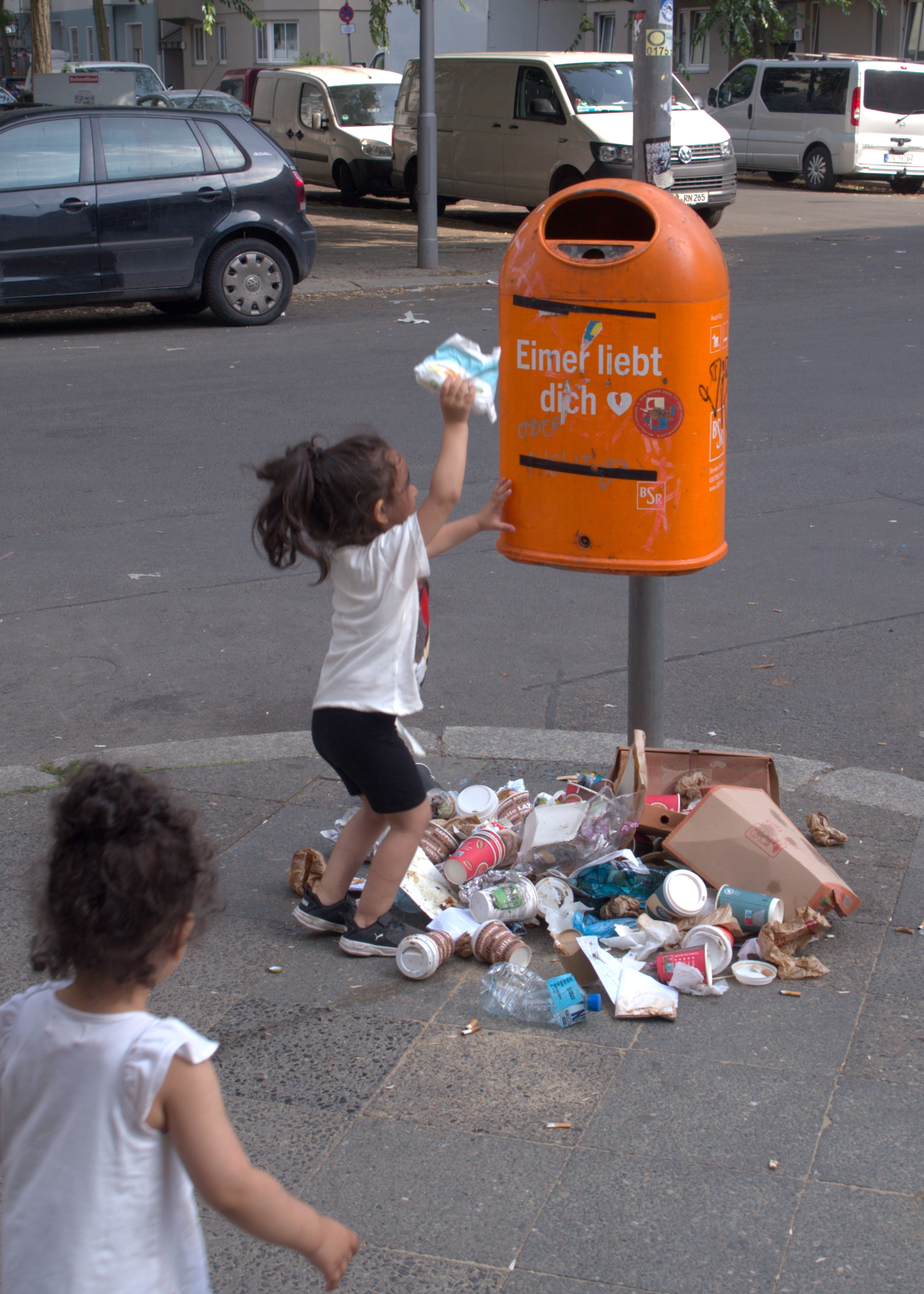 Una niña hace esfuerzos por tirar sus propios pañales a una papelera demasiado alta para ella. Berlín. Serie 'el soporte' de Ibán Ojea.