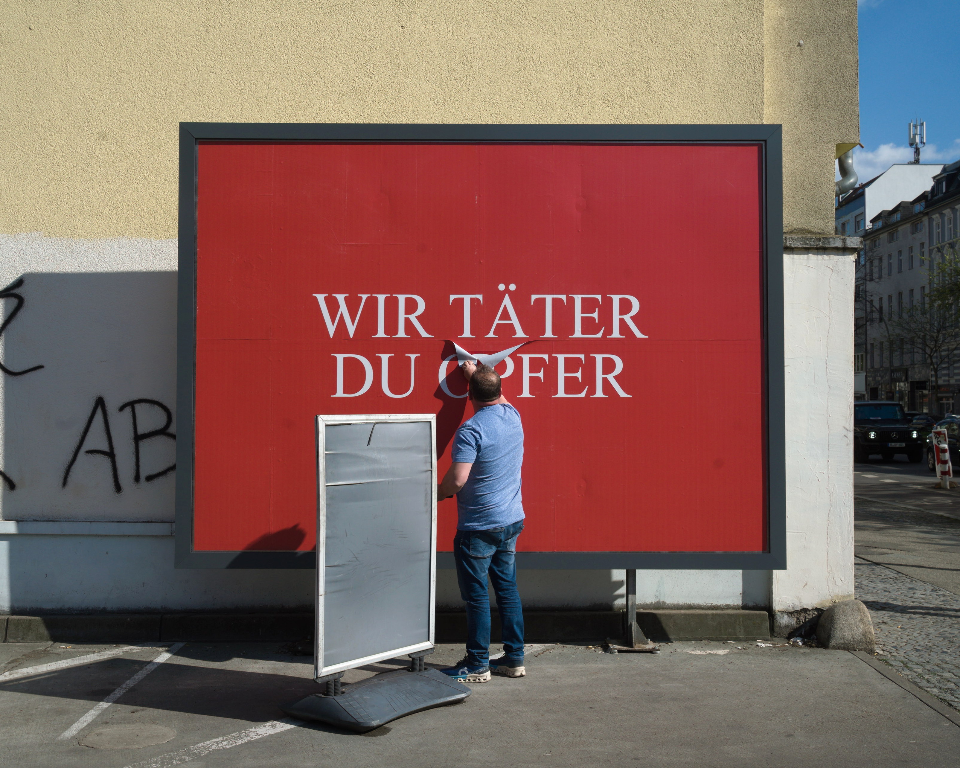 Alguien está destruyendo un cartel con el mensaje 'Wir Täter, du Opfer'. Serie 'el soporte' de Ibán Ojea.