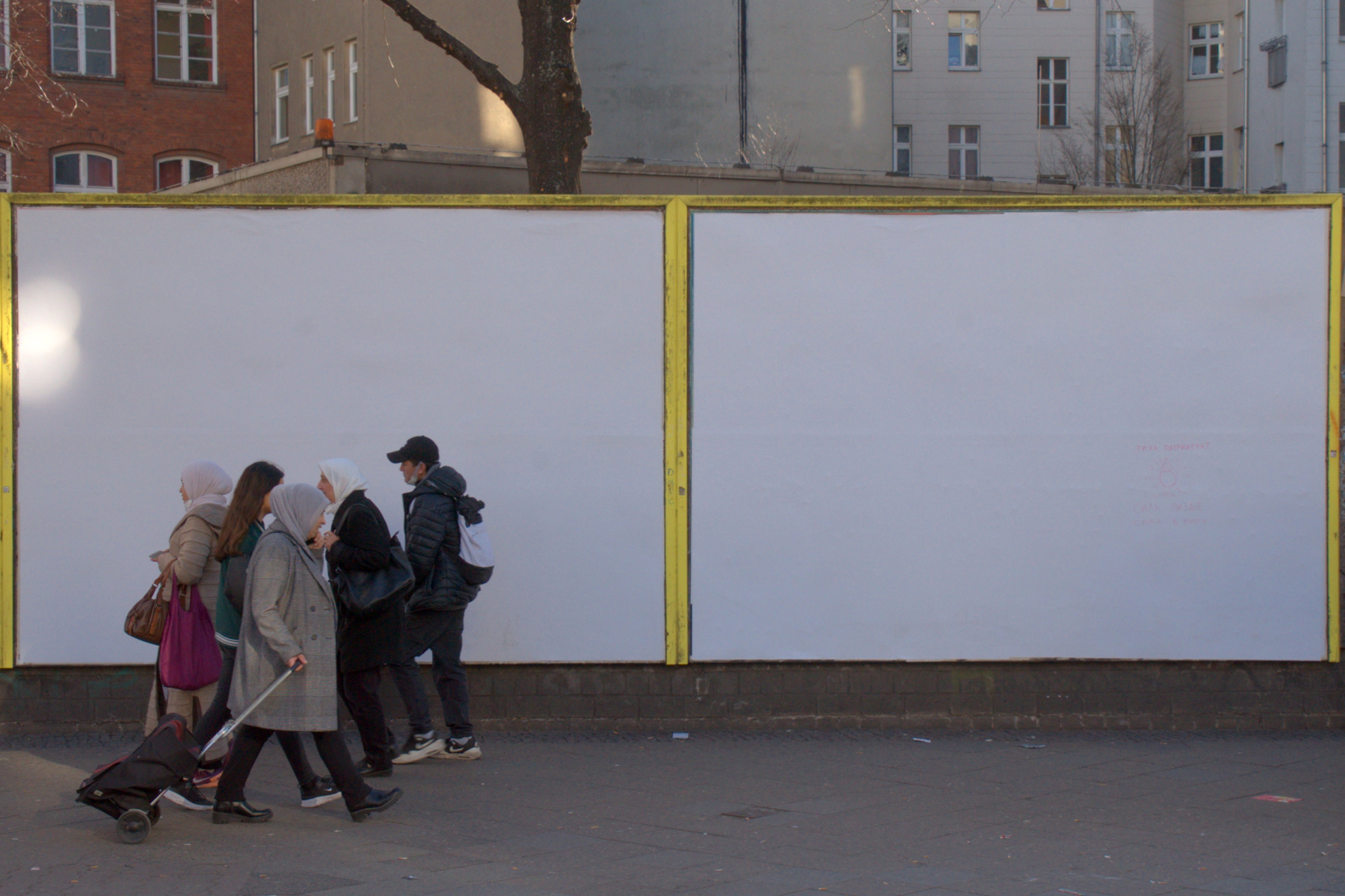 Un grupo de gente pasan al lado de unos carteles publicitarios en blanco. Serie 'el soporte' de Ibán Ojea: exploración de fotografía conceptual en Berlín.