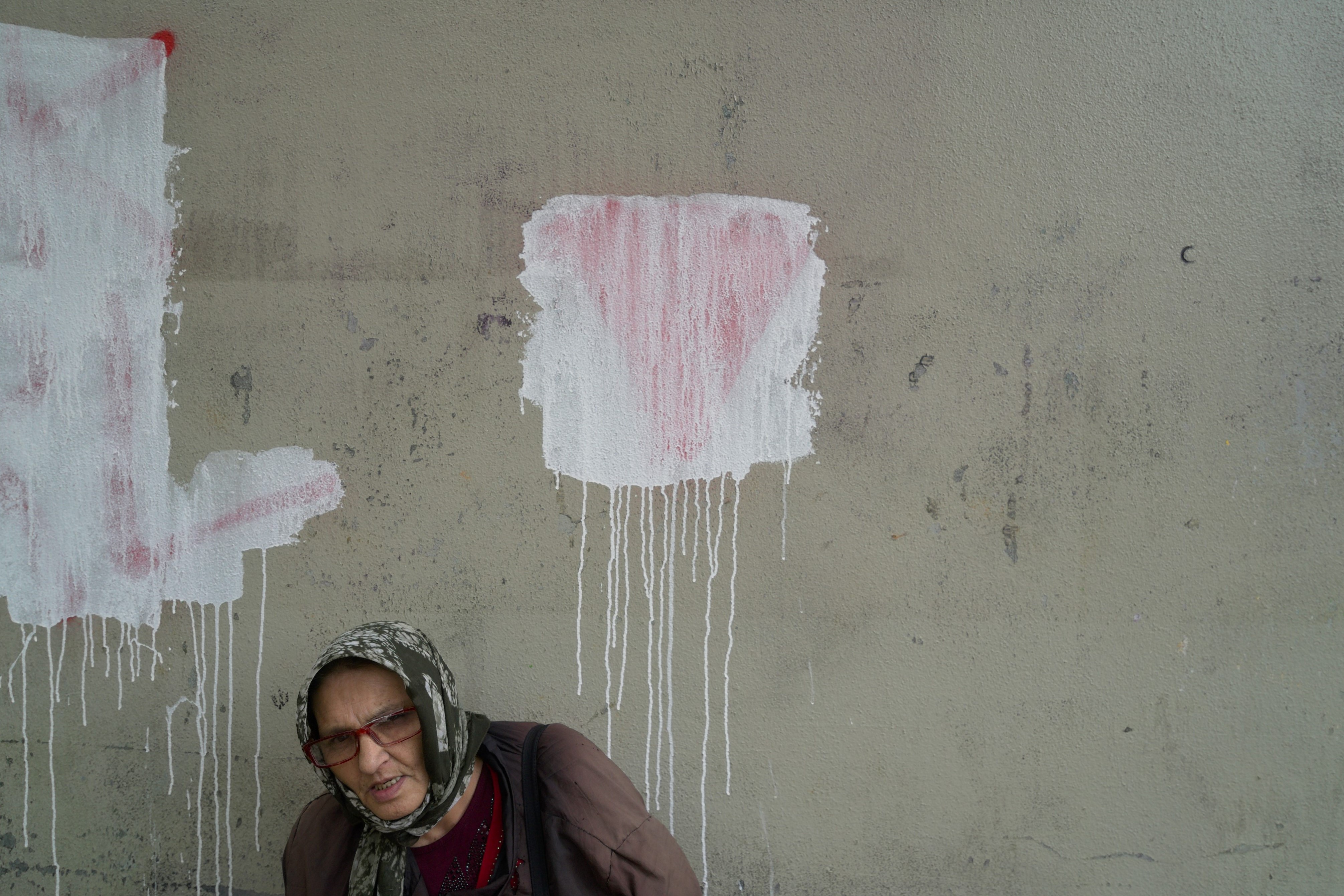 Retrato de mujer ante pared con un corazón borrado que todavía se ve detrás. Serie 'el soporte', fotografía de Ibán Ojea.